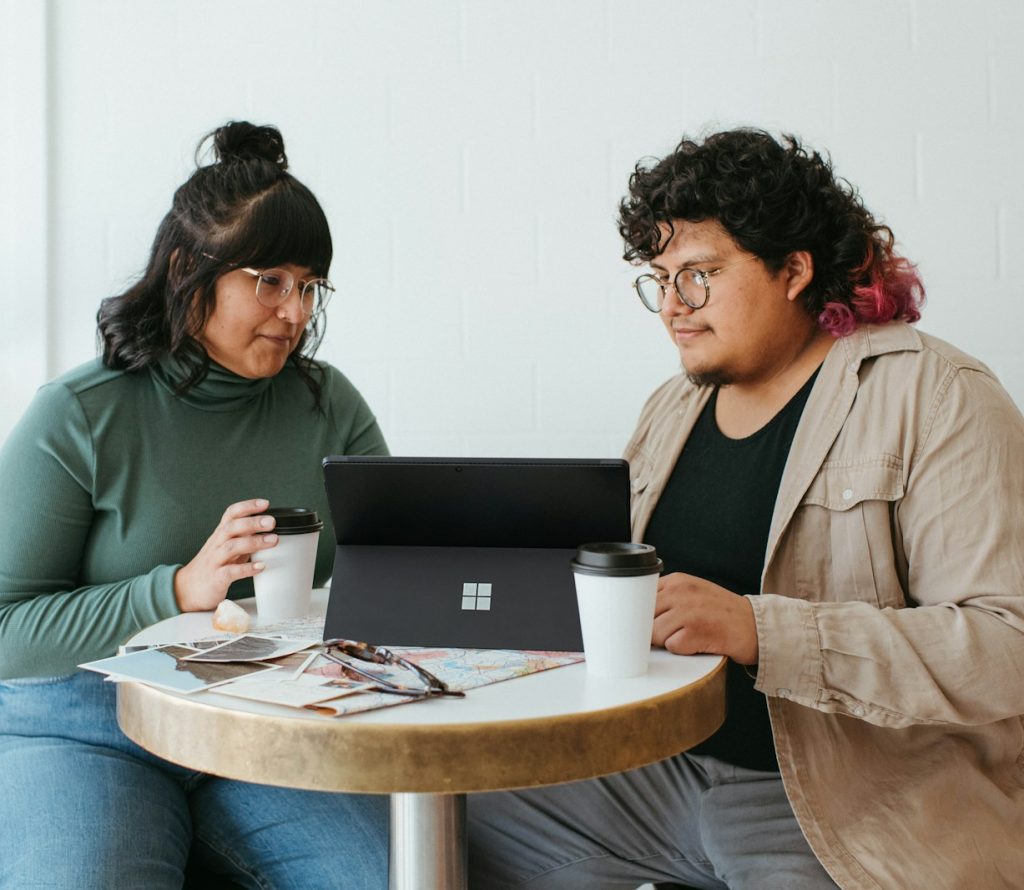 two women sitting at a table with a laptop